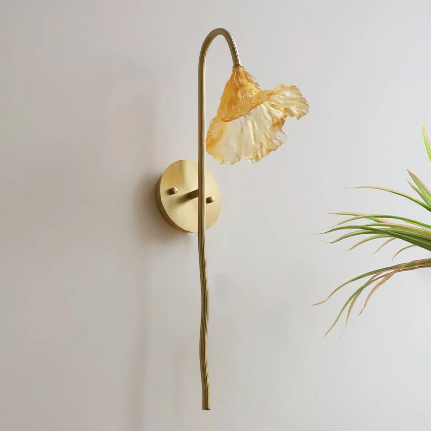 Lotus Amber Wall Sconce side close-up detail showing slender brass stem and unlit ruffled amber glass shade with green potted plant