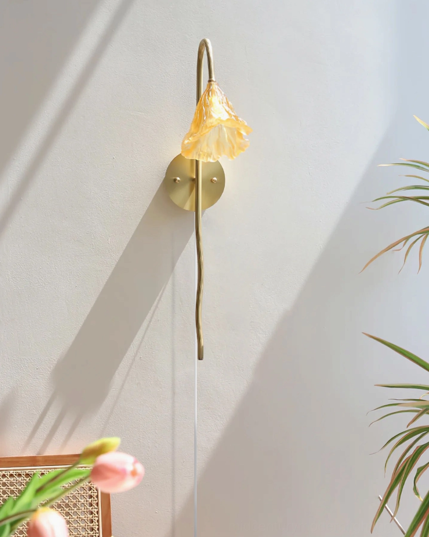 Illuminated lotus amber wall sconce showing soft shadow on wall and brass hardware details with tulip decoration