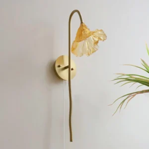 Lotus Amber wall sconce mounted on interior wall with potted plant, three-quarter perspective showing curved brass arm