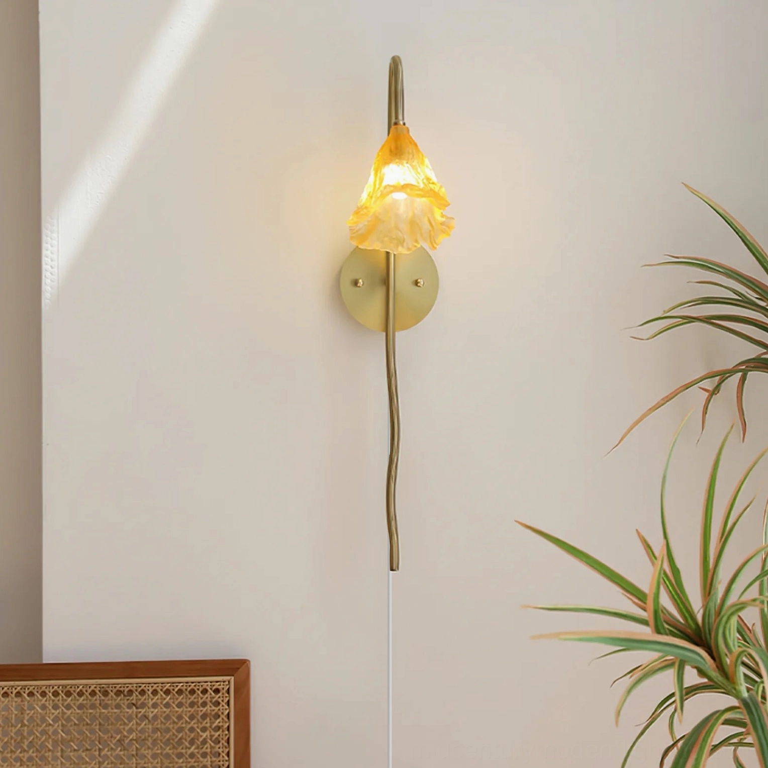 Lit lotus amber wall sconce casting warm glow with visible power cord and rattan wall décor background
