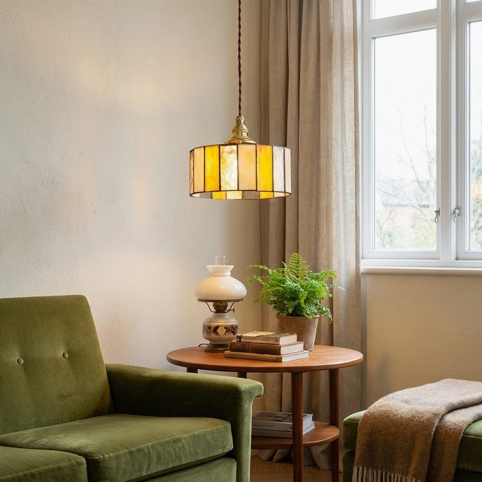 Cozy lounge corner with warm stained glass drum pendant lamp mounted above green armchair, eye-level view
