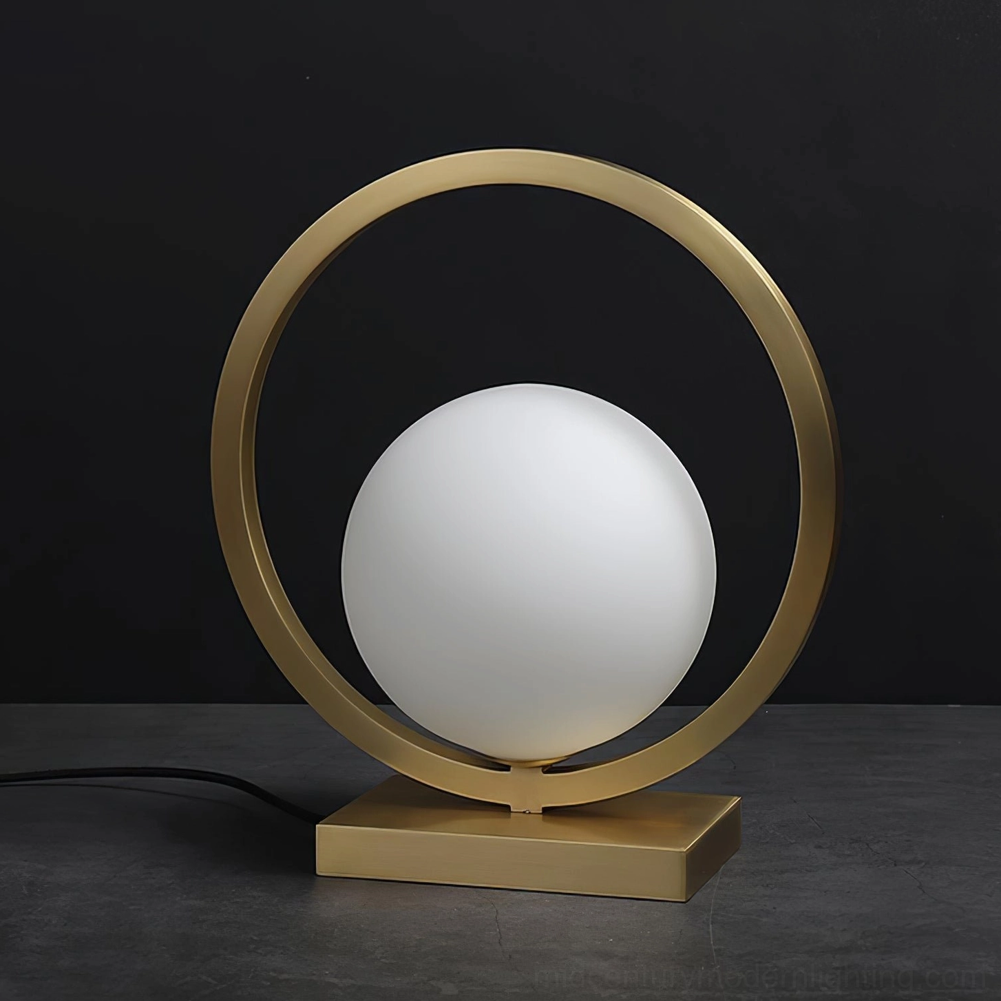 Lunar Brass Table Lamp on dark desk surface showing power cord and square metal base