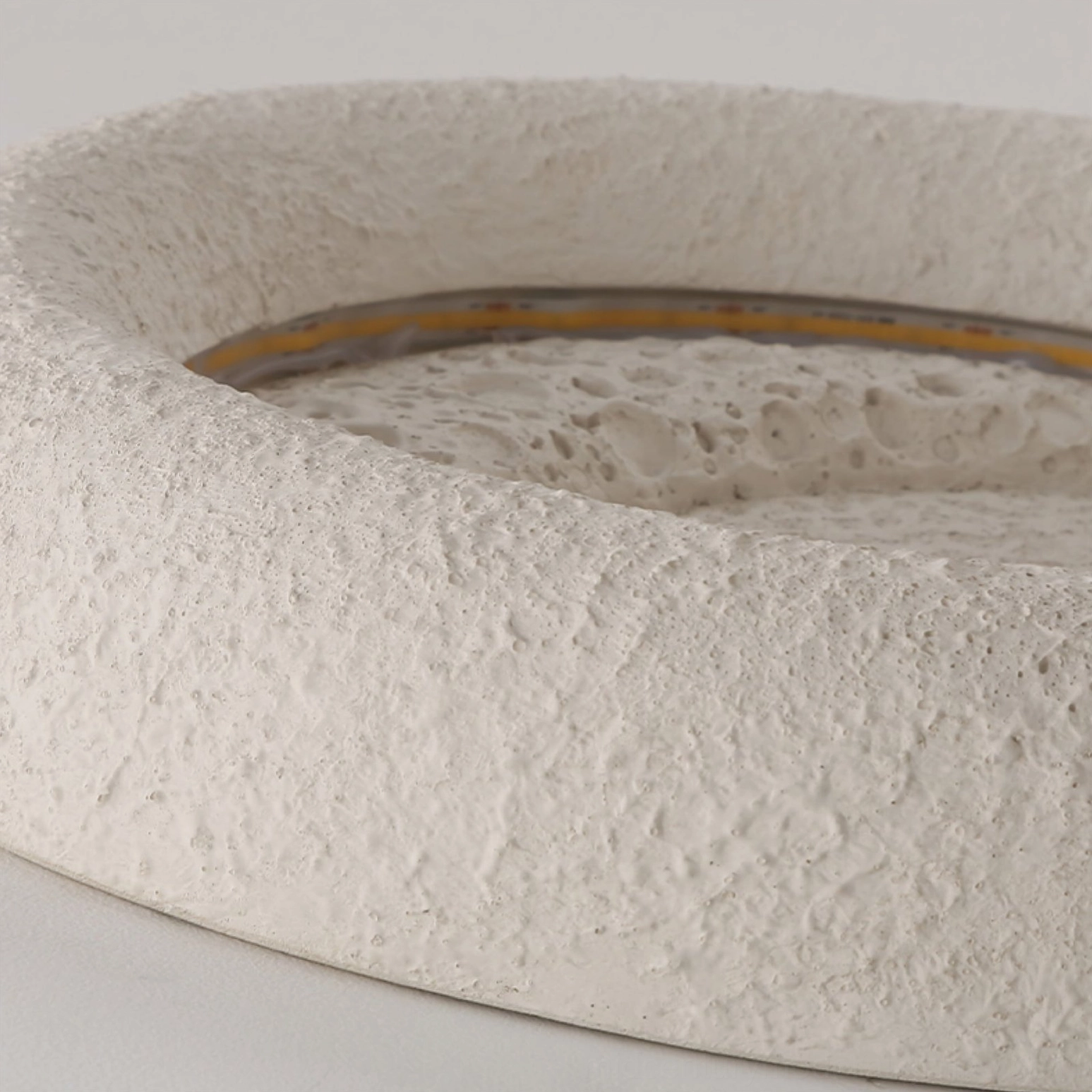 Lunar glow ceiling lamp ultra close-up showing visible LED light strip and porous matte resin texture