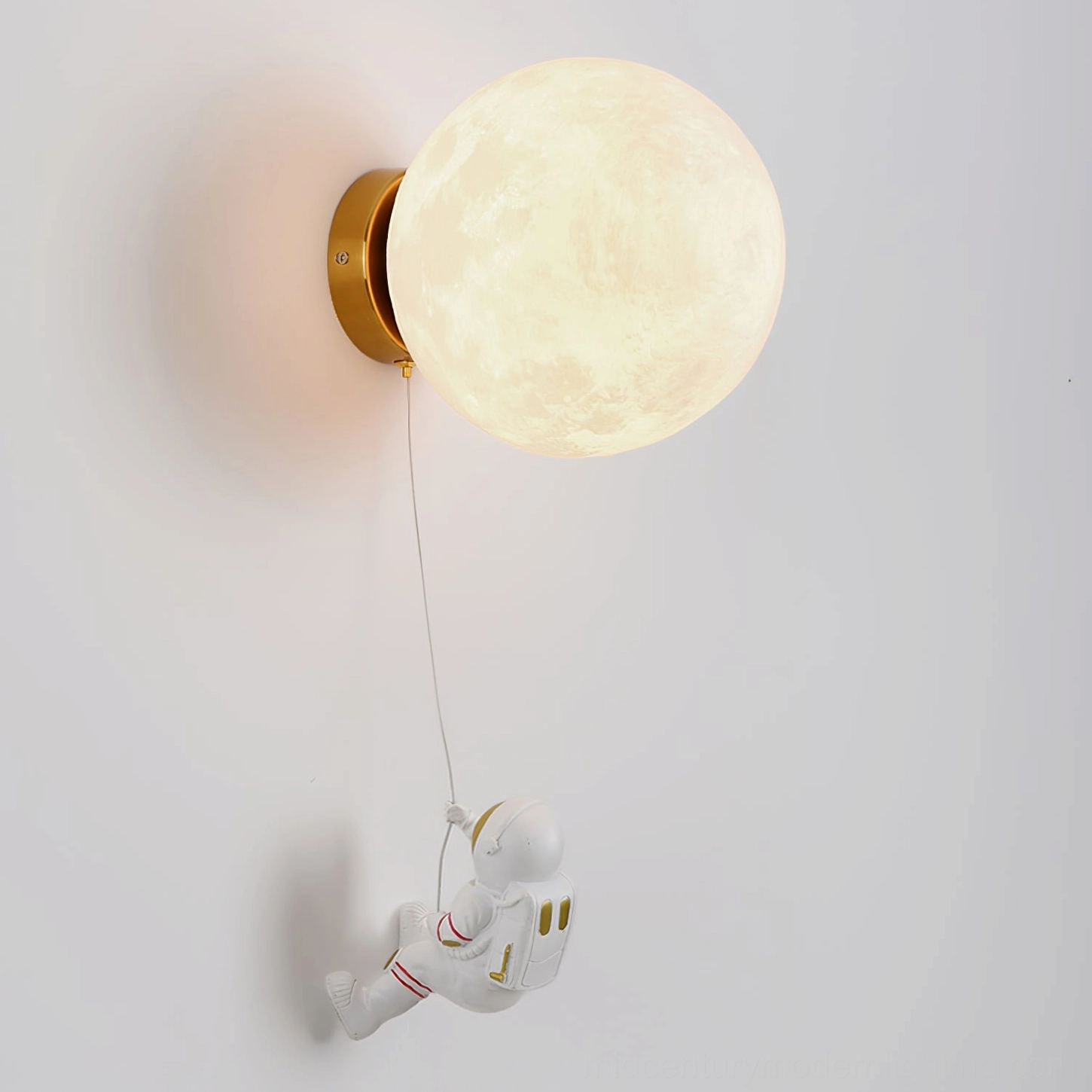 Warm-lit lunar globe wall lamp with gold metal base and resin astronaut figurine on white wall