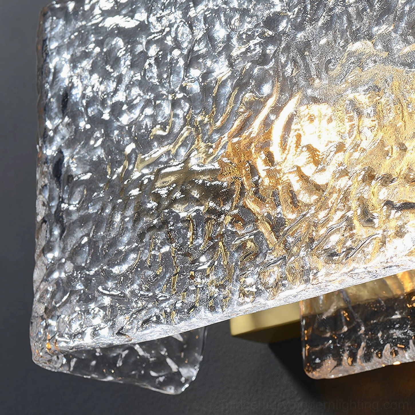 Lunea wall sconce low angled macro view showcasing textured clear glass and glowing E14 LED bulb detail