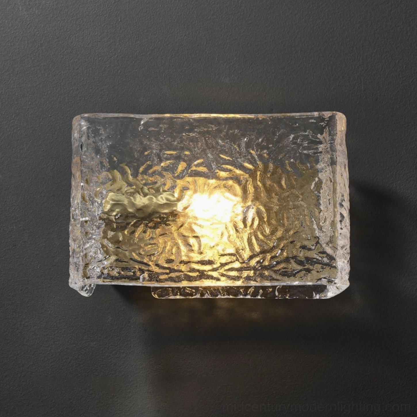Close-up detail of Lunea rippled glass diffuser with glowing warm internal light on grey wall