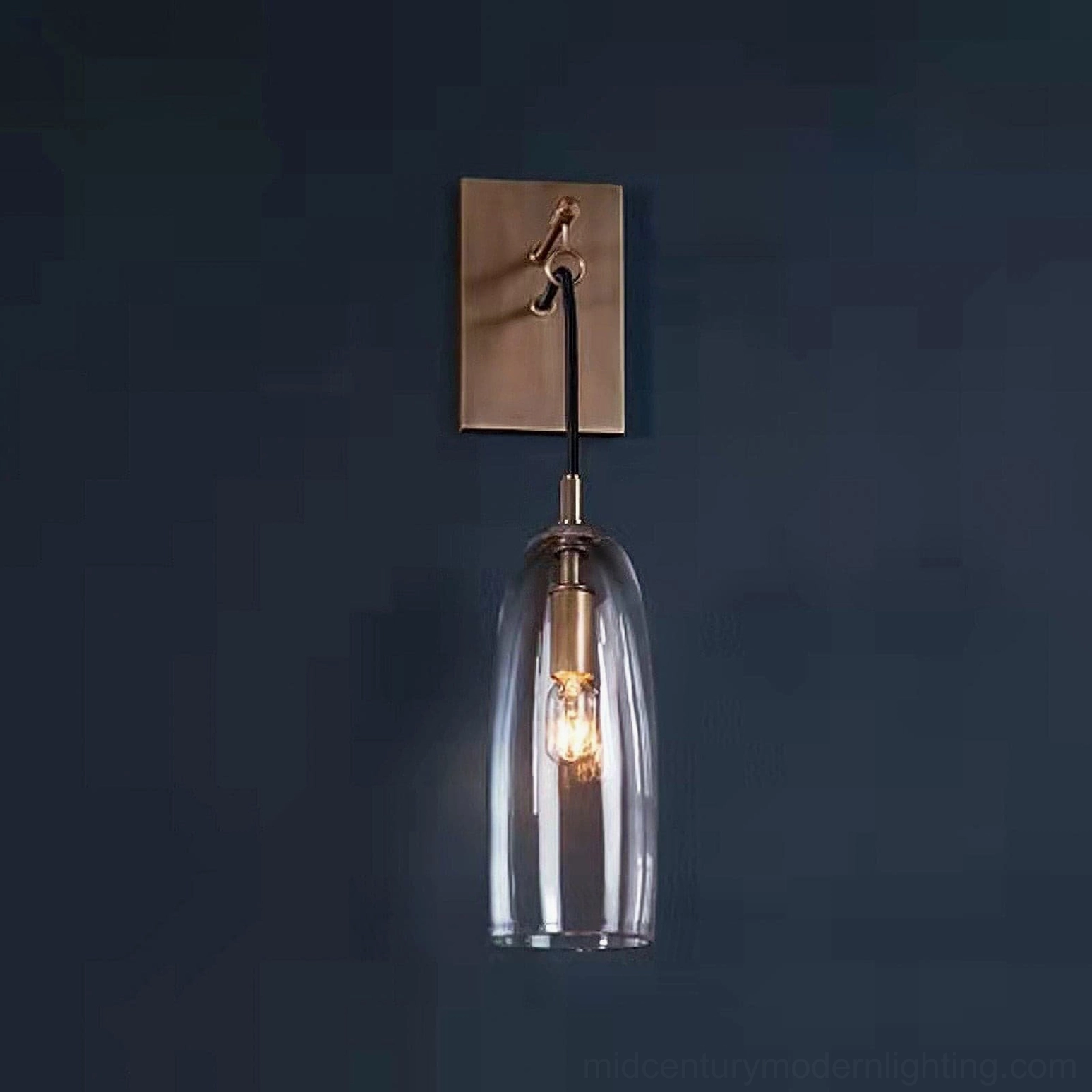 Contemporary wall-mounted sconce with brass base and clear glass shade, architectural lighting