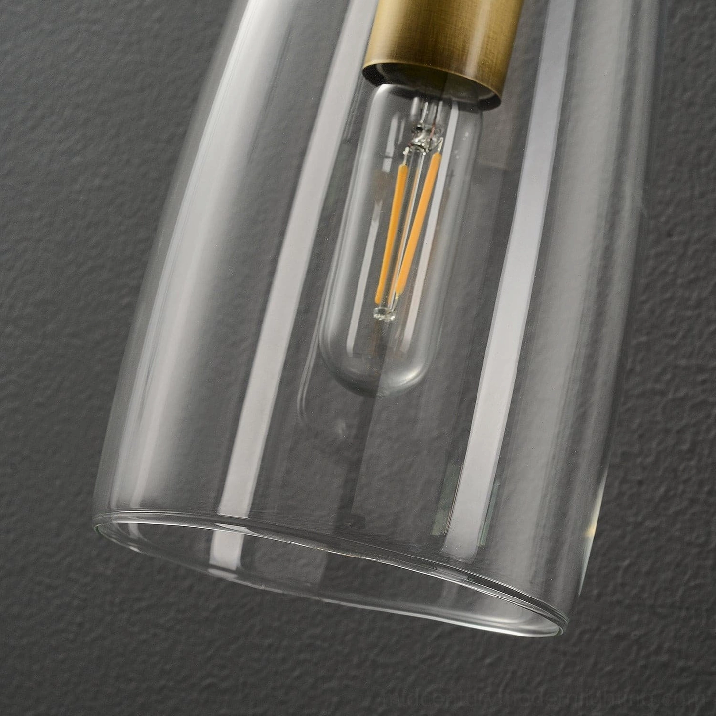 Minimalist glass wall sconce with brass base in modern home office or study setting
