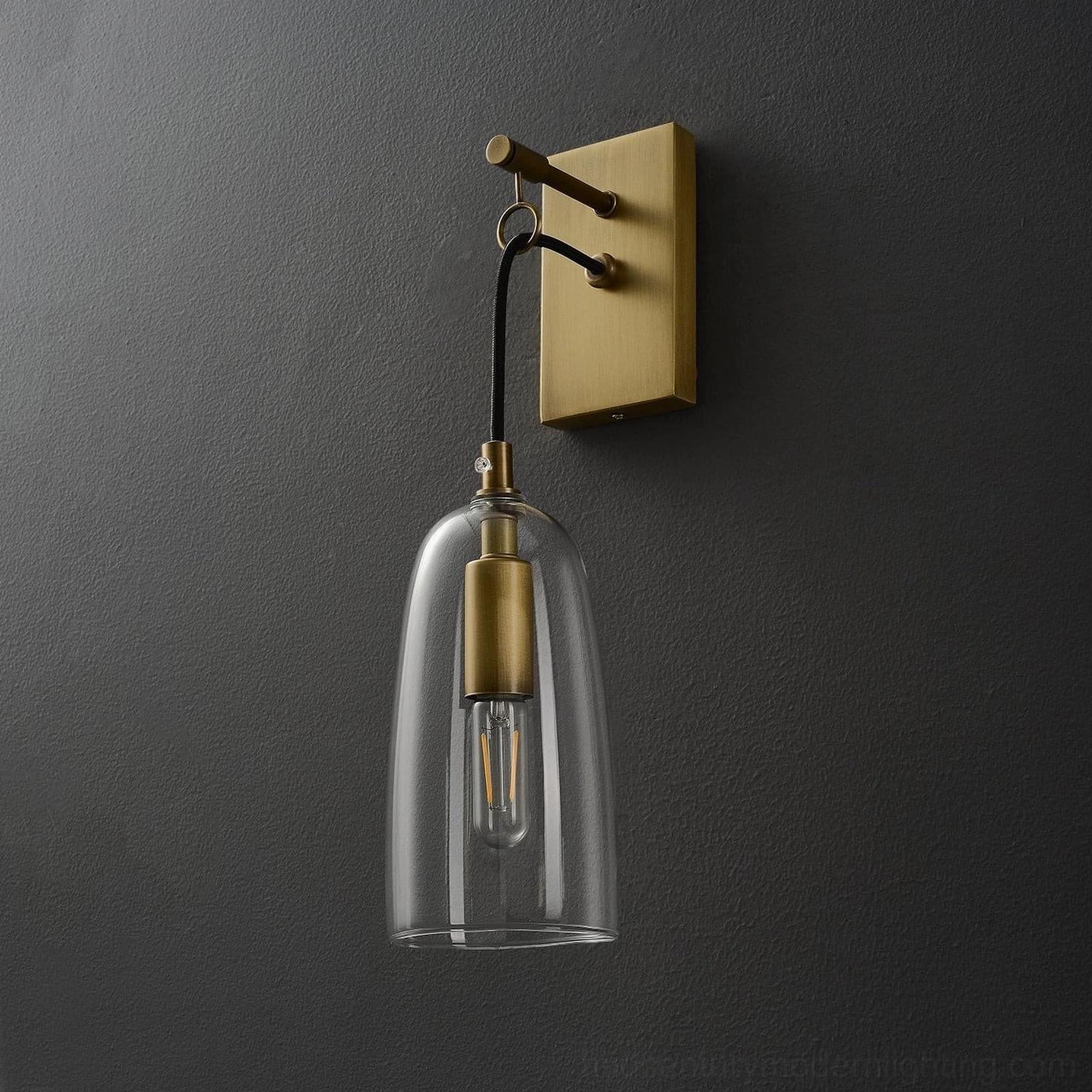 Modern minimalist brass wall sconce with tapered clear glass cylinder, architectural detail view