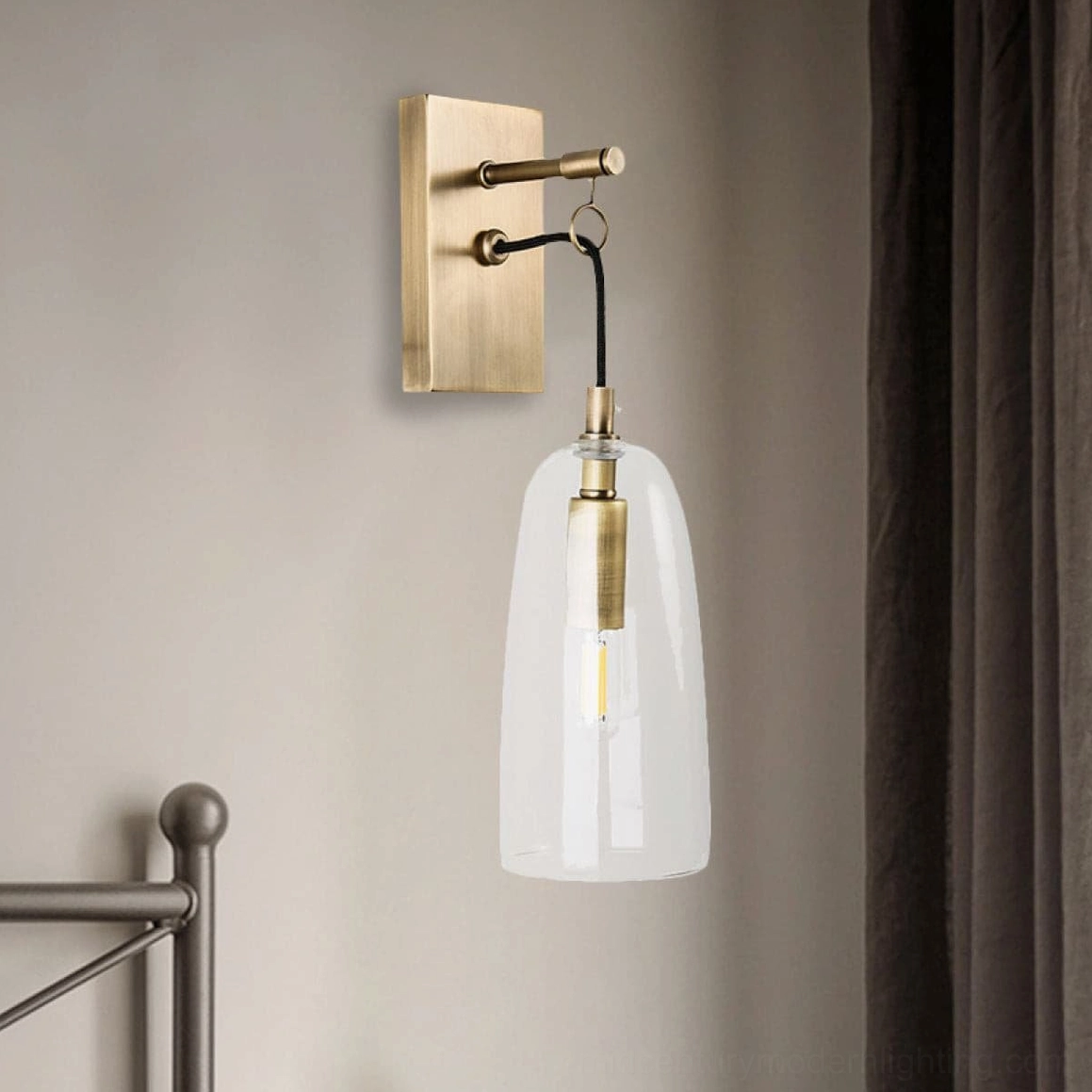 Sleek brass wall sconce with illuminated filament bulb creating warm ambiance in bedroom setting