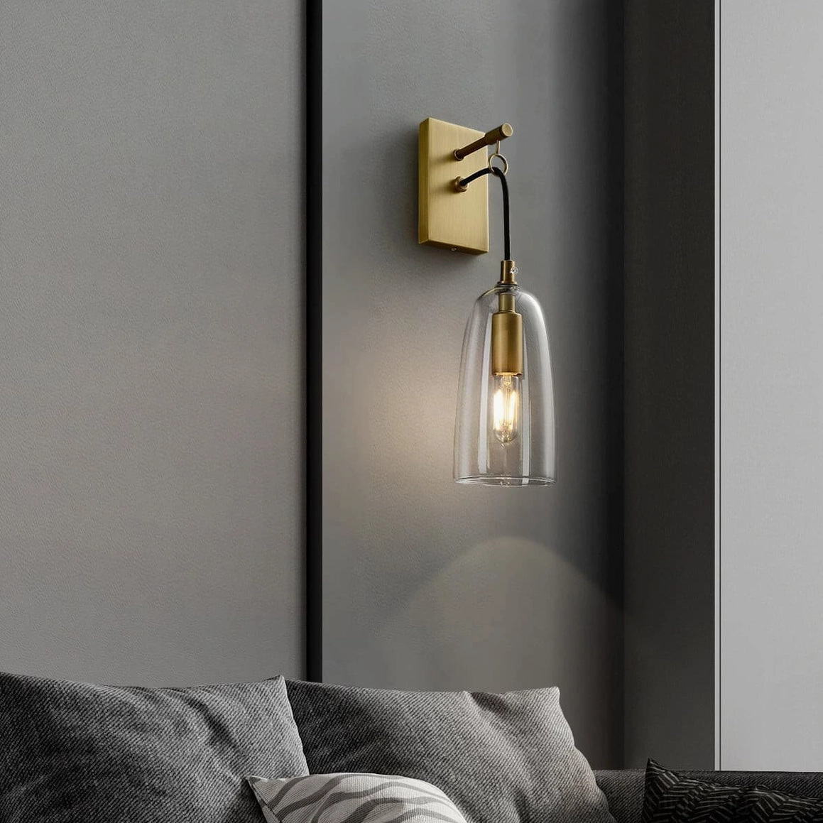 Architectural brass wall sconce with clear shade providing focused ambient illumination