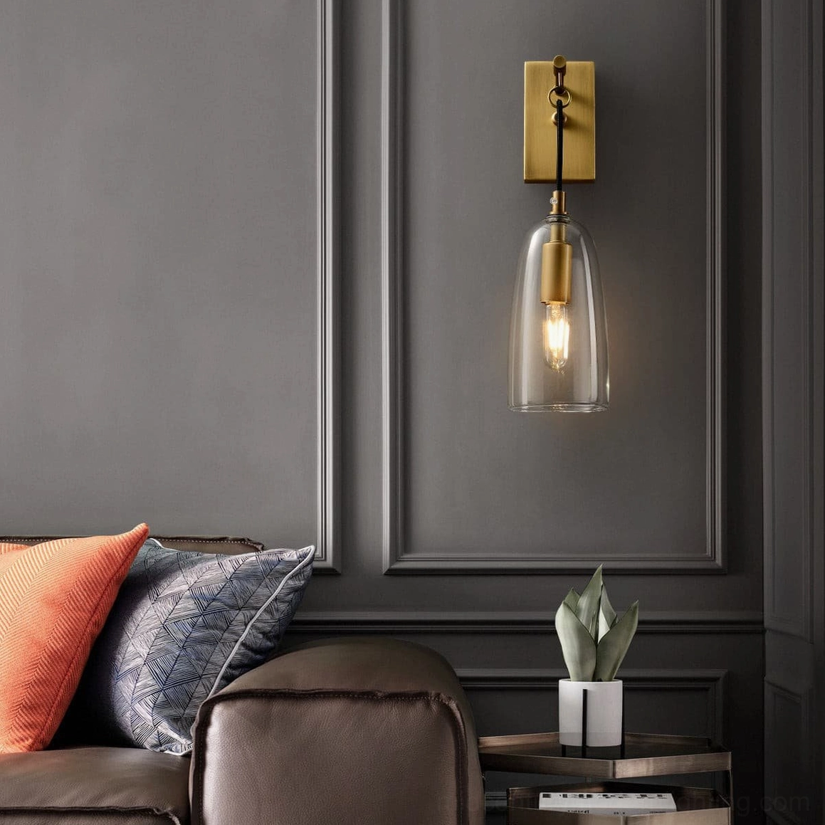 Modern wall sconce with clear glass cylinder and polished brass finish, contemporary styling