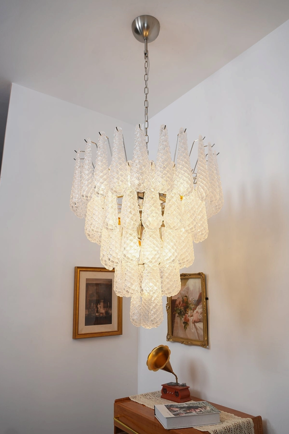 Illuminated white Murano glass chandelier with cascading pendants in luxury residential living room with framed artwork and vintage furnishings