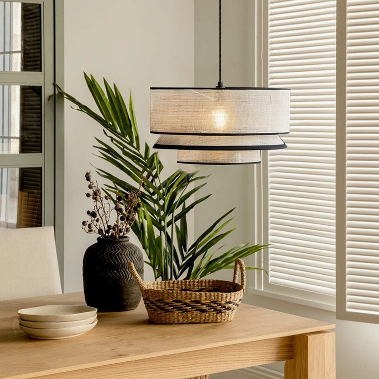 Two-tiered woven pendant light hanging above dining table in warm minimalist interior, wooden table setting with neutral decor