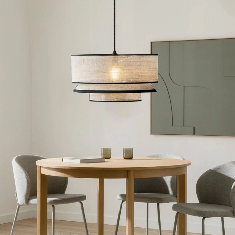 Side view of two-tiered woven pendant light in compact casual dining area with round light wood table and grey upholstered chairs