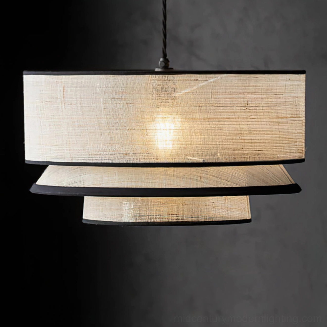 Three-tiered sculptural drum pendant lamp close-up product view with natural woven texture on dark studio background
