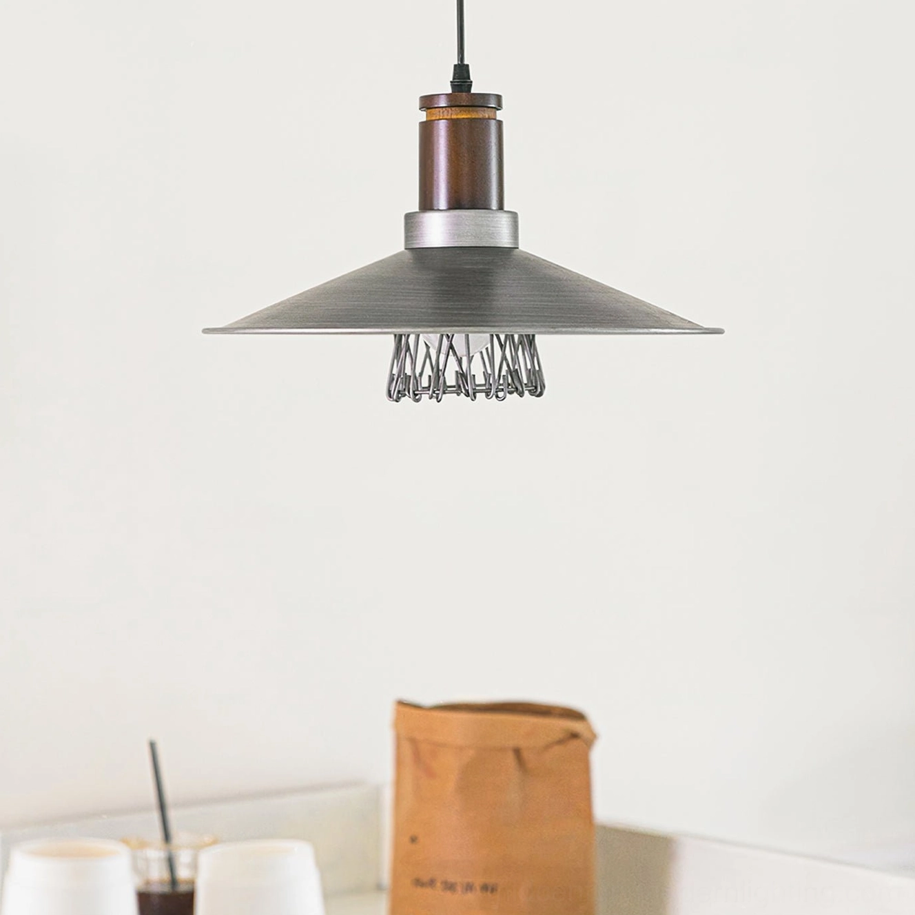 Bottom close-up detail of Lyfa pendant showing exposed Edison bulb with wire cage guard and brushed metal trim