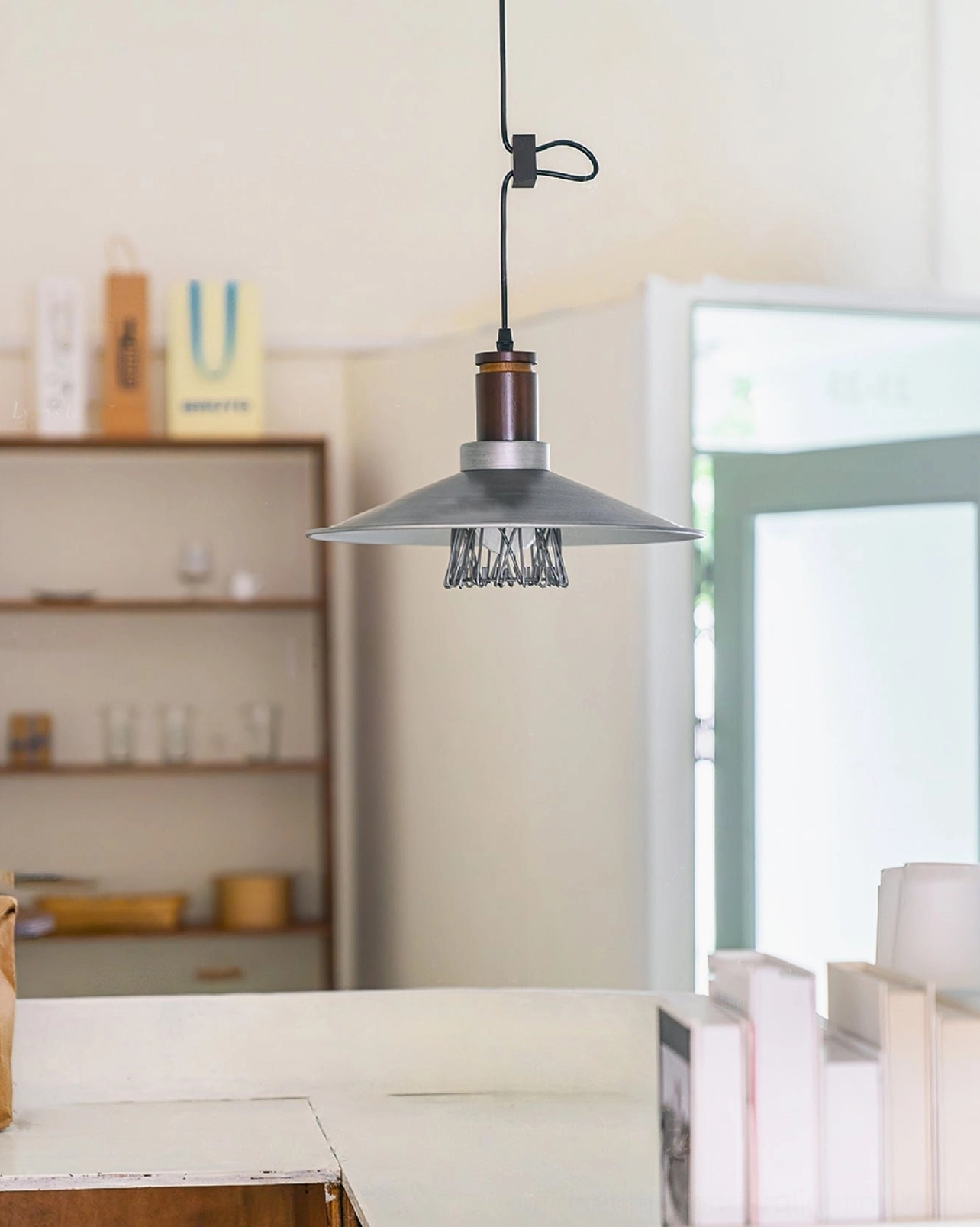 Lyfa pendant suspended above wooden shelf in home study corner with warm neutral decor