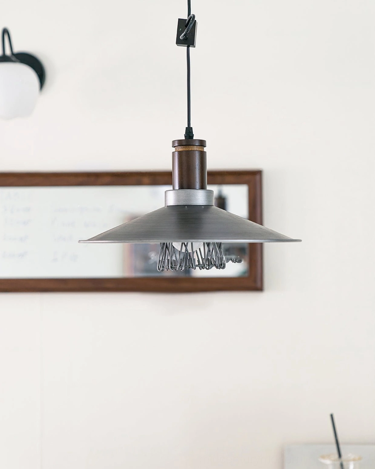 Lyfa industrial pendant lamp hanging beneath wall mirror in minimalist modern home interior