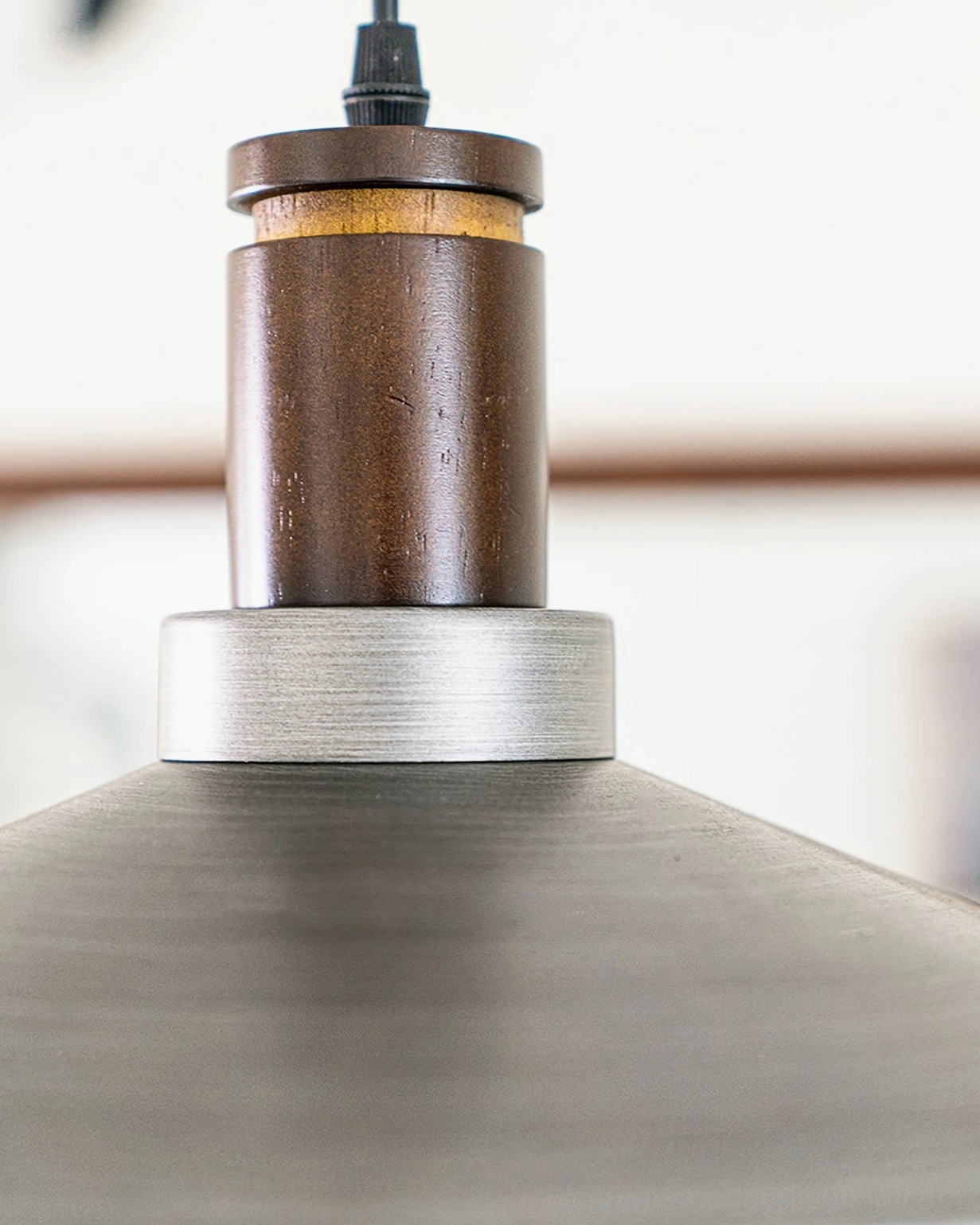 Side view close-up of Lyfa pendant base showing dark walnut wood collar and brushed metal shade transition