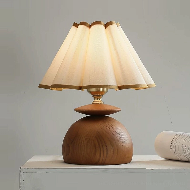 Mabel pleated table lamp beige shade close-up flat lay studio showing gold-trimmed pleated linen and wood grain