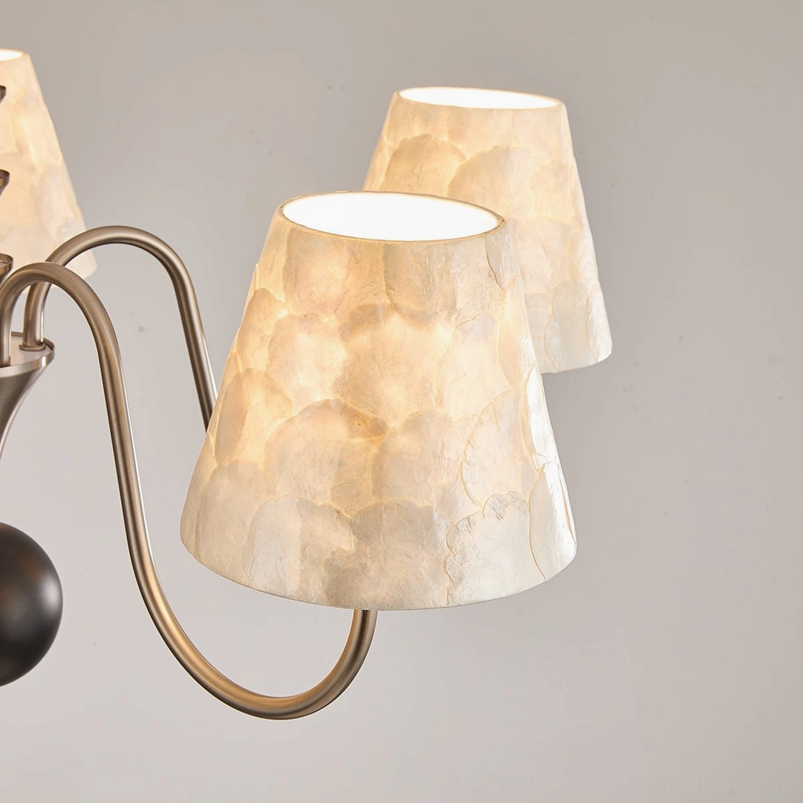 Extreme close-up side angle of capiz shell chandelier displaying smooth shell texture and brushed metal craftsmanship