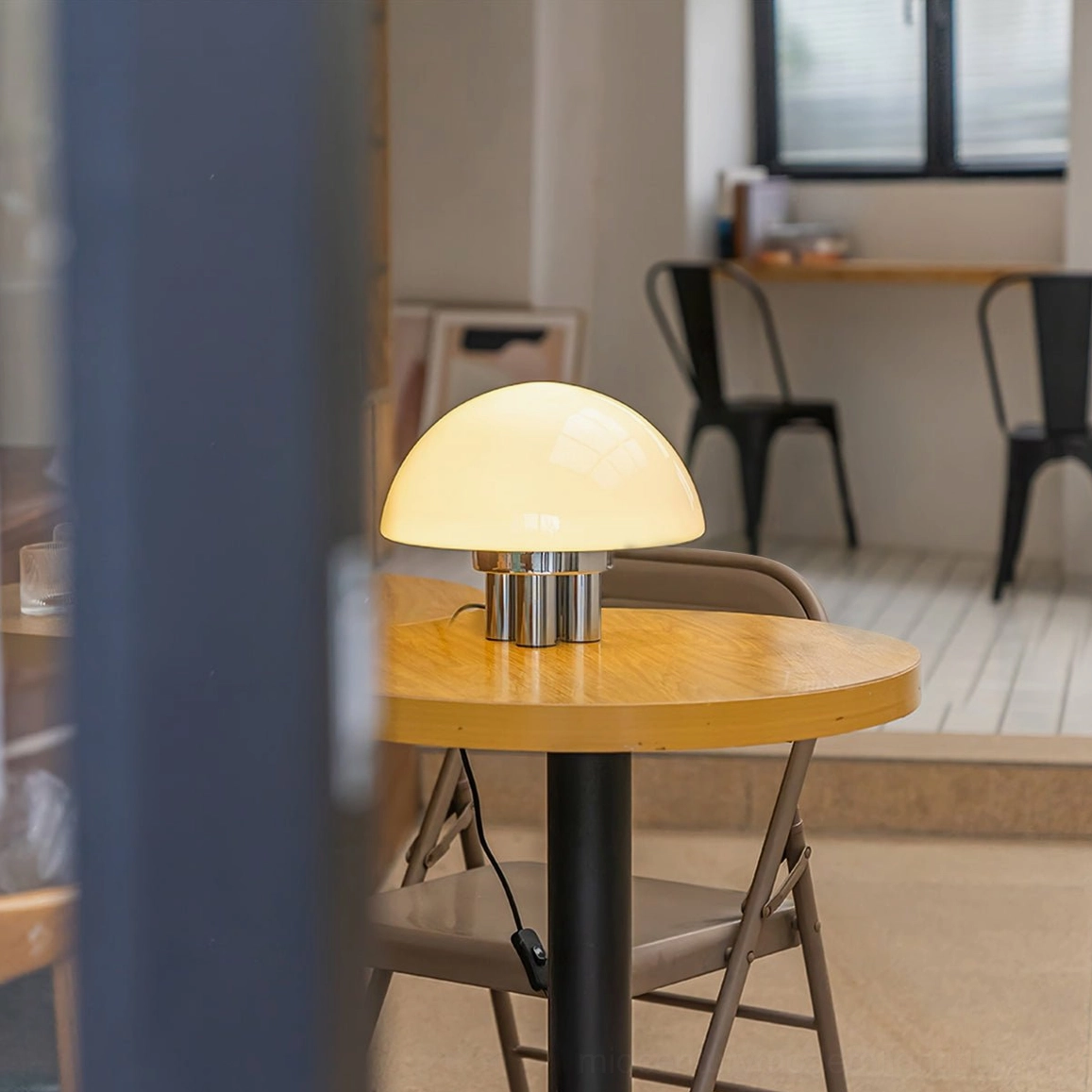 Mushroom table lamp creating warm ambient light on small round wooden dining table