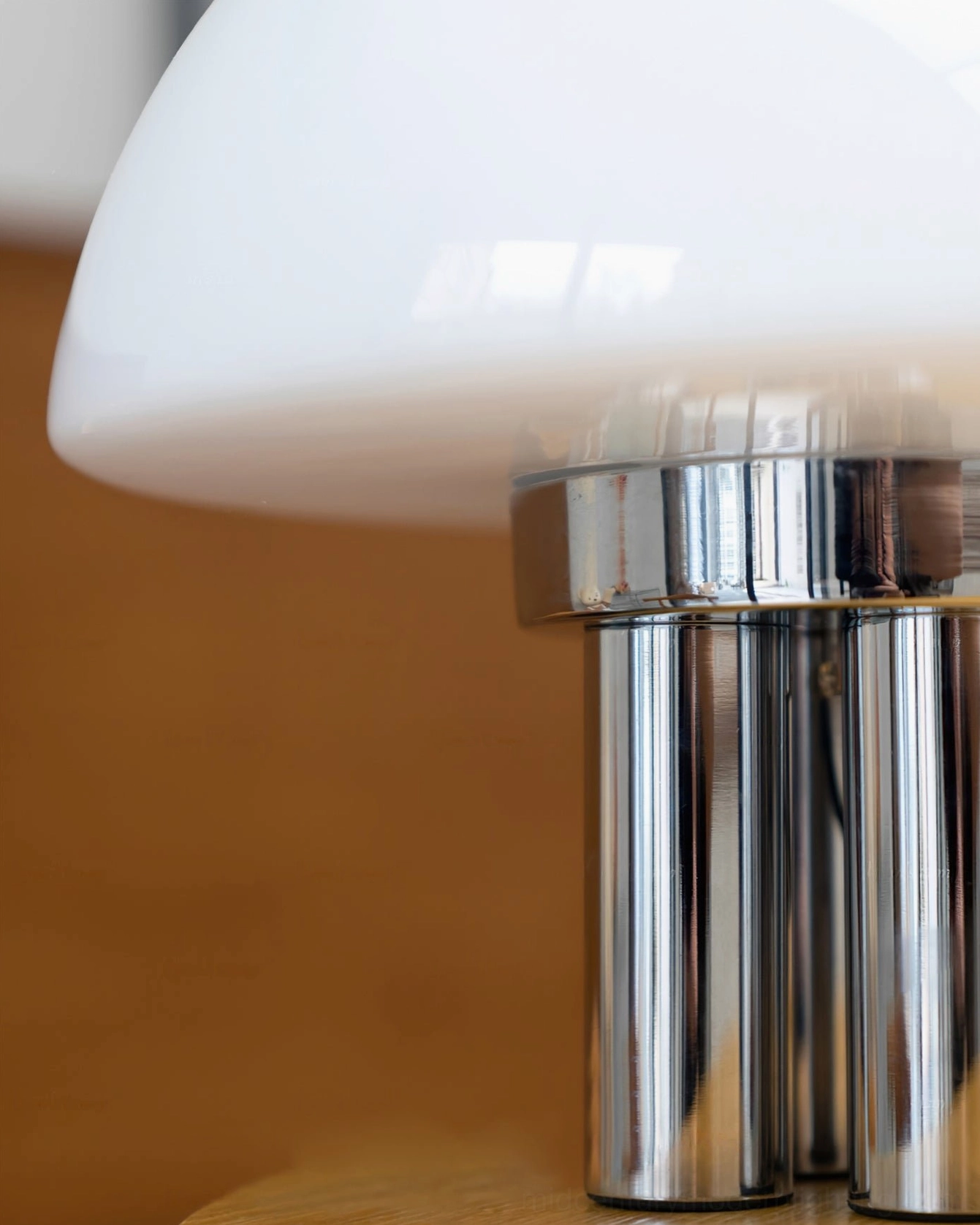 Minimalist chrome and white mushroom table lamp on neutral modern interior setting