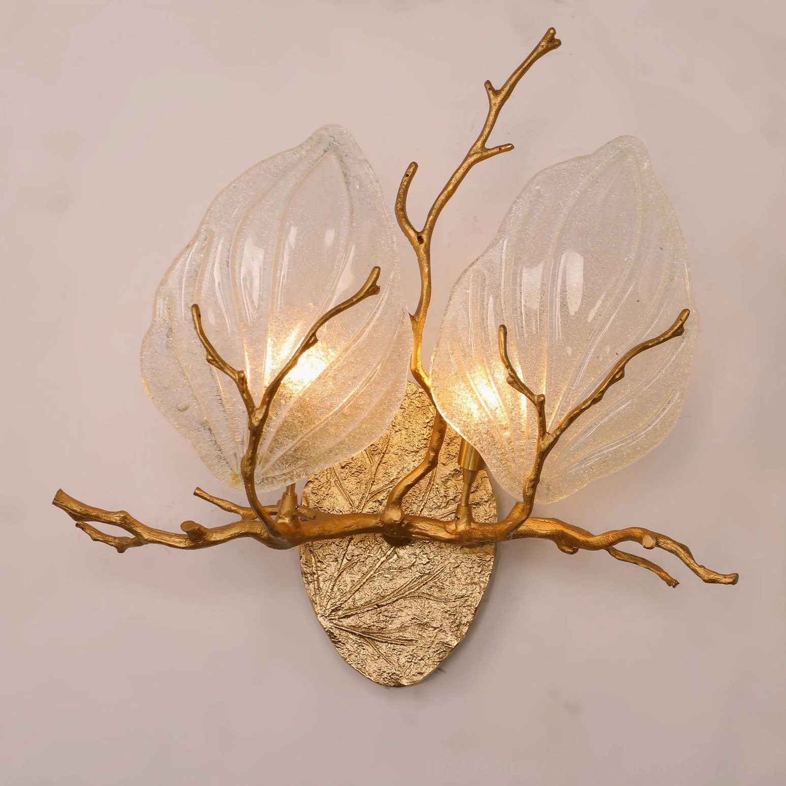 Magnolia brass leaf sconce showing dual frosted glass forms with raised veins and hand-cast brass horizontal branch detail