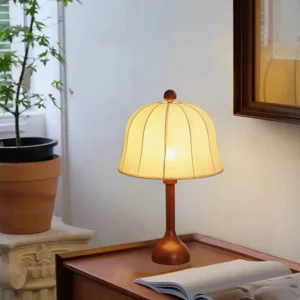 Malcolm table lamp on bedroom nightstand with warm glowing yellow fabric shade and brown wood base, cozy bedside lighting