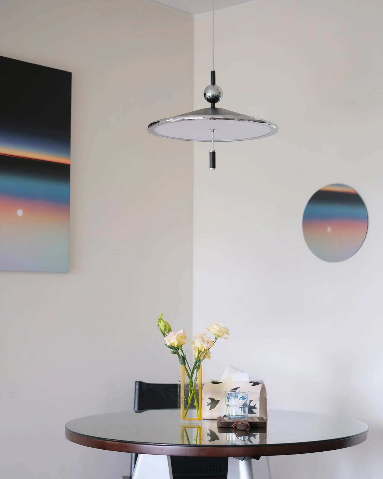 Malmo pendant fixture with chrome and black finish above small round dining corner with floral centerpiece
