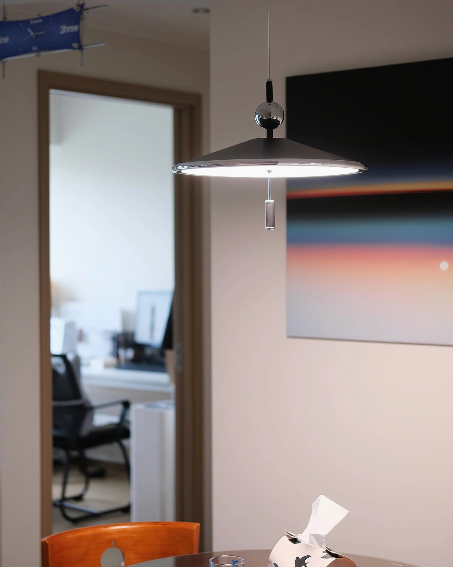 Malmo geometric pendant lamp creating focused lighting beside modern gradient wall artwork