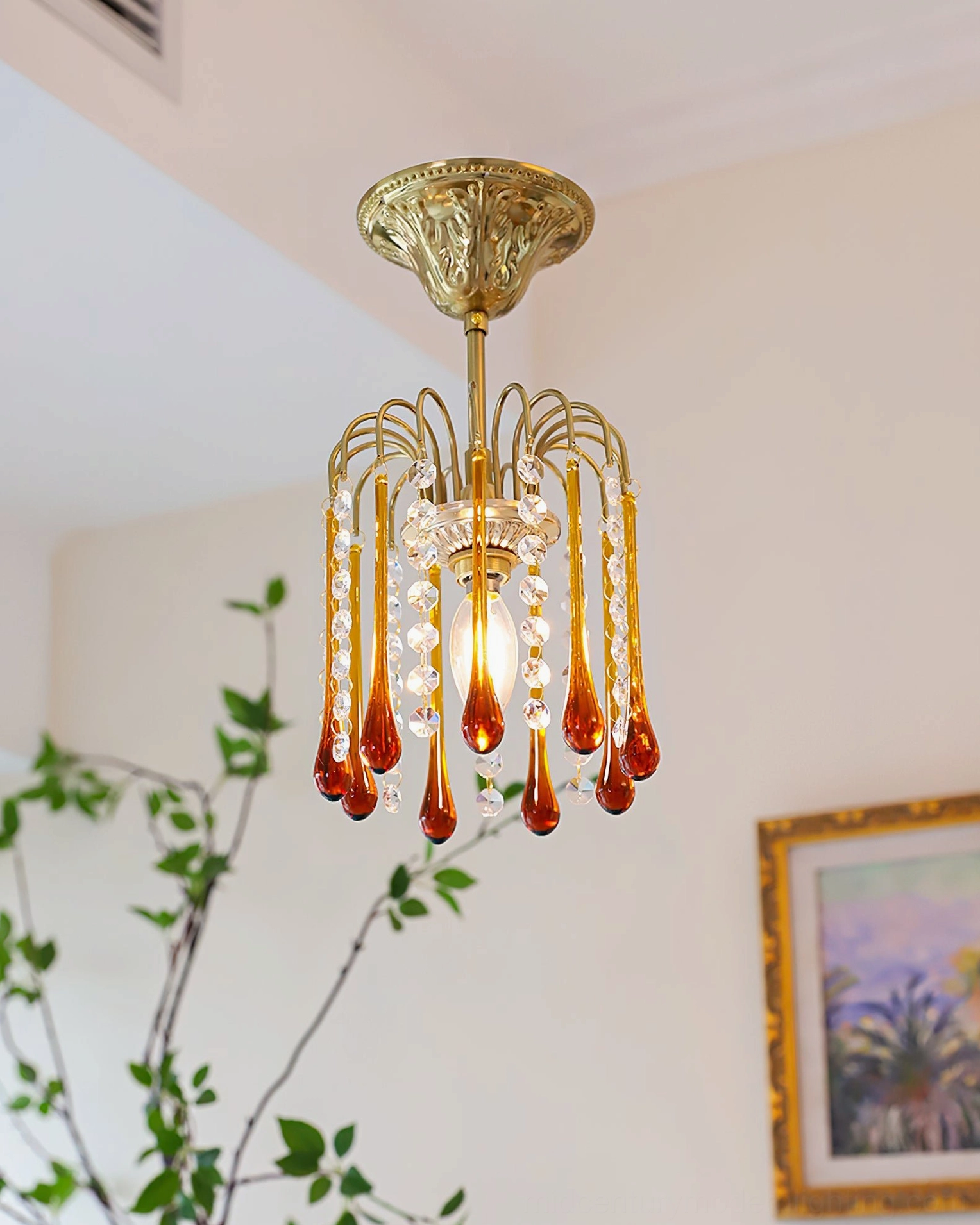 Low angle view of Maltose crystal ceiling light illuminated above vintage home interior with landscape painting and green plants