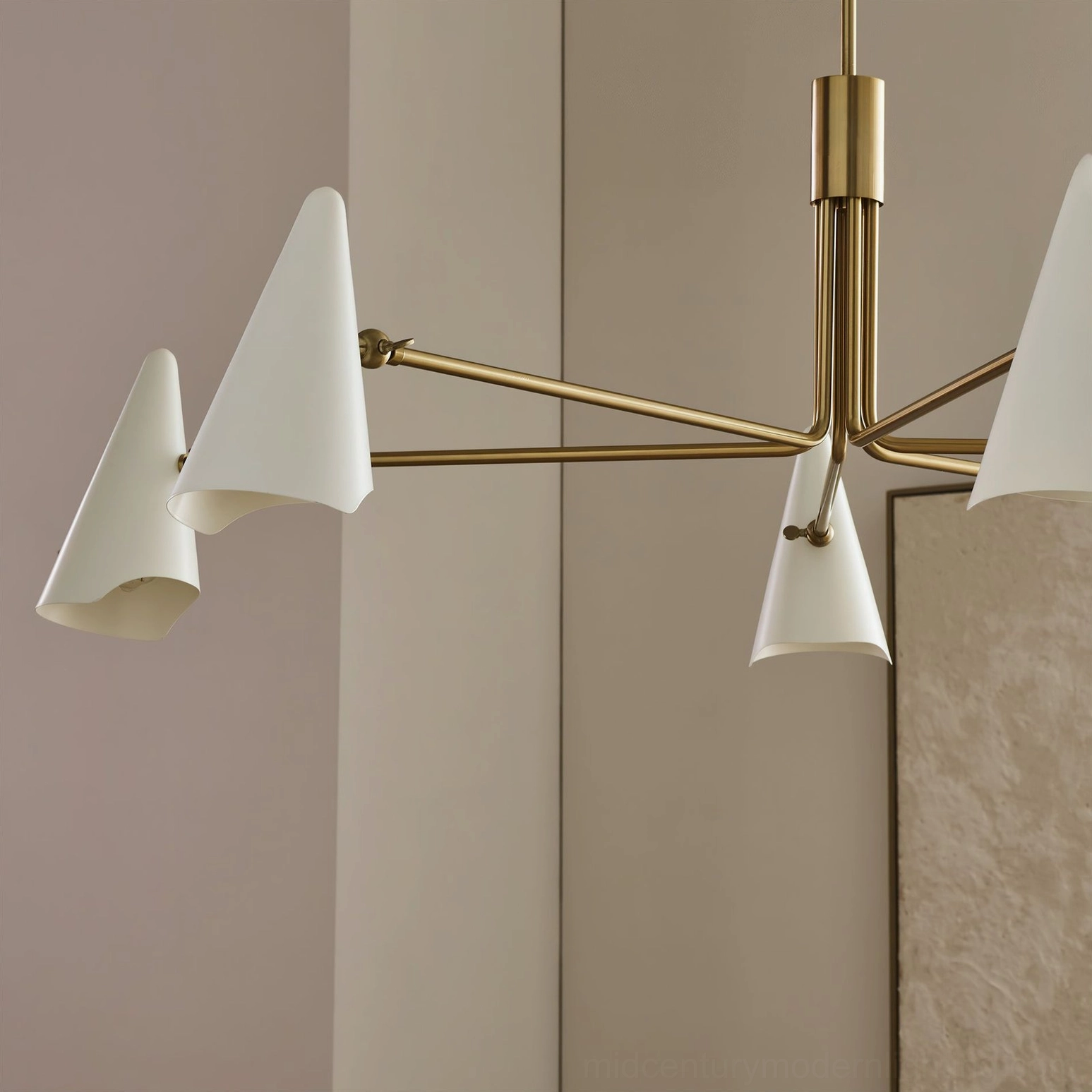 Side angled close-up of Mancini chandelier brass arm and white tapered shade against beige wall