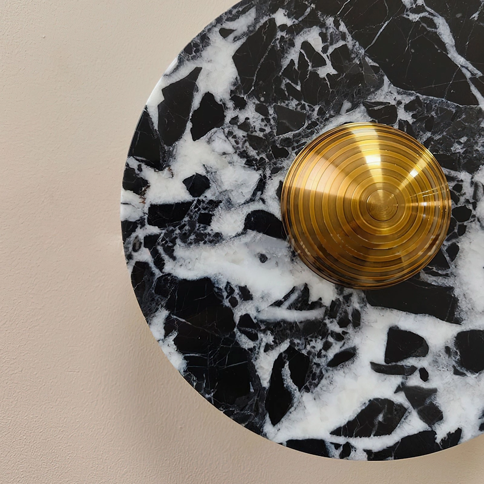 Extreme close-up overhead view of oversized black marble wall lamp with brass central fixture and LED detail