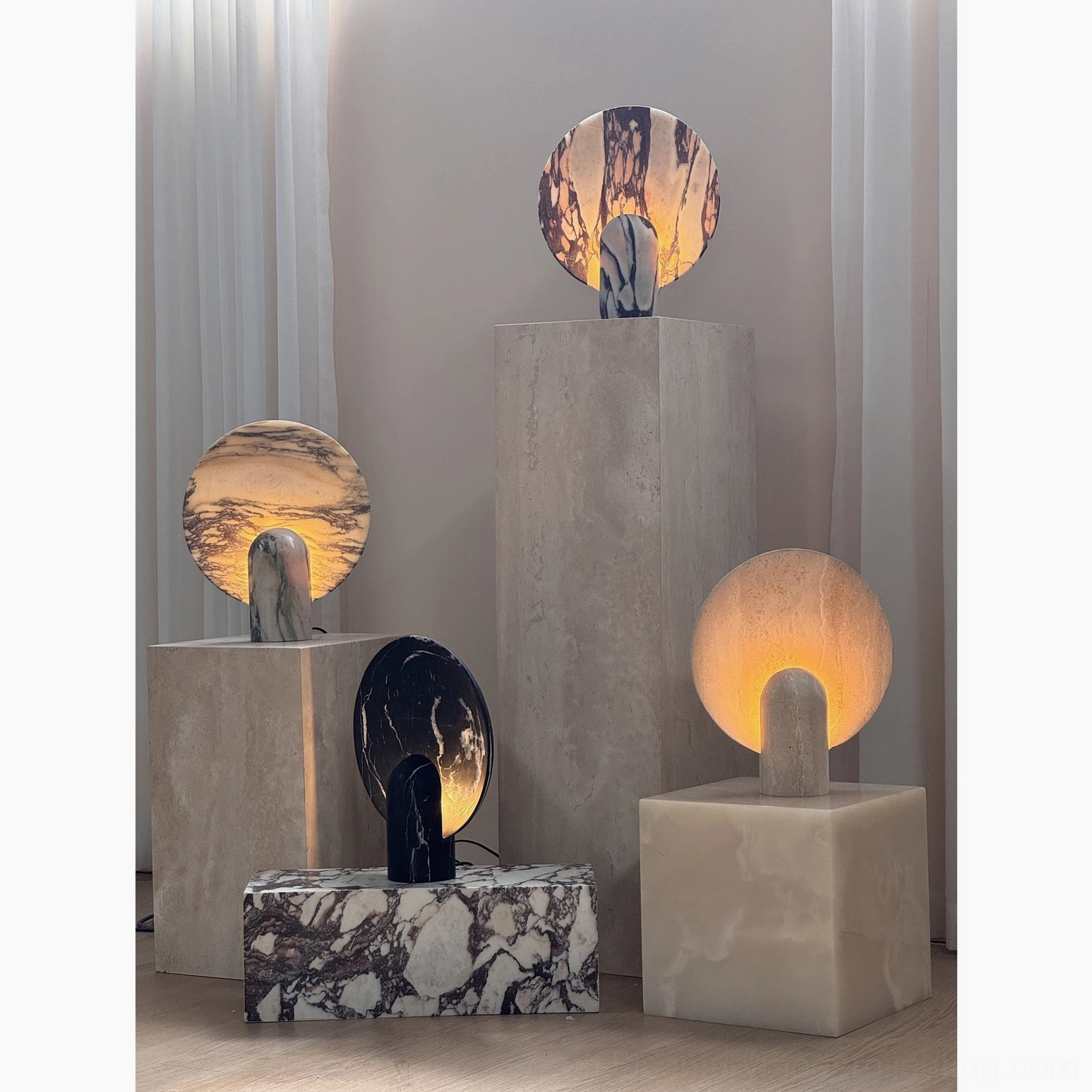 Multiple modern marble table lamps in various colorways arranged in minimalist home interior with curtains and warm neutral decor tones