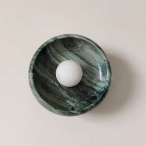 Modern marble wall lamp mounted on beige interior wall, overhead flat view displaying swirling stone pattern and flush design