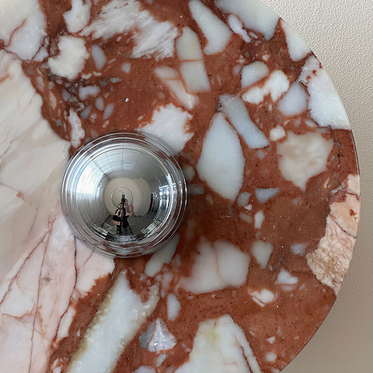 Detailed close-up view of marble wall lamp showing natural veining patterns and brass fixture installation