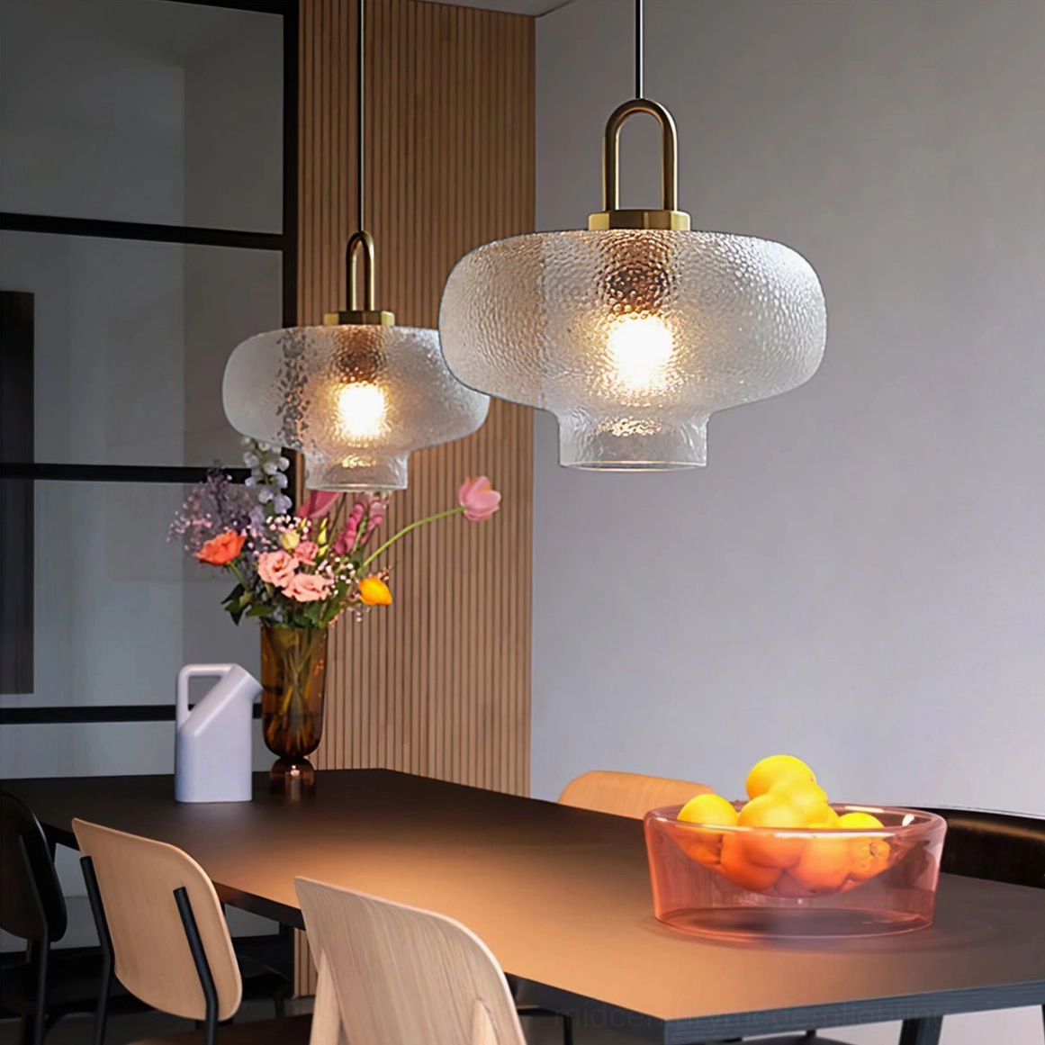 Pair of Marco textured glass pendants with brass hardware above modern dining room table with wooden surface