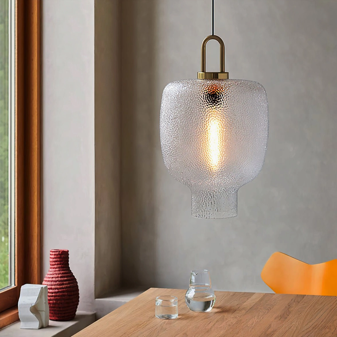 Short barrel Marco pendant lamp with rippled clear glass and brass accents in home dining corner, eye-level perspective