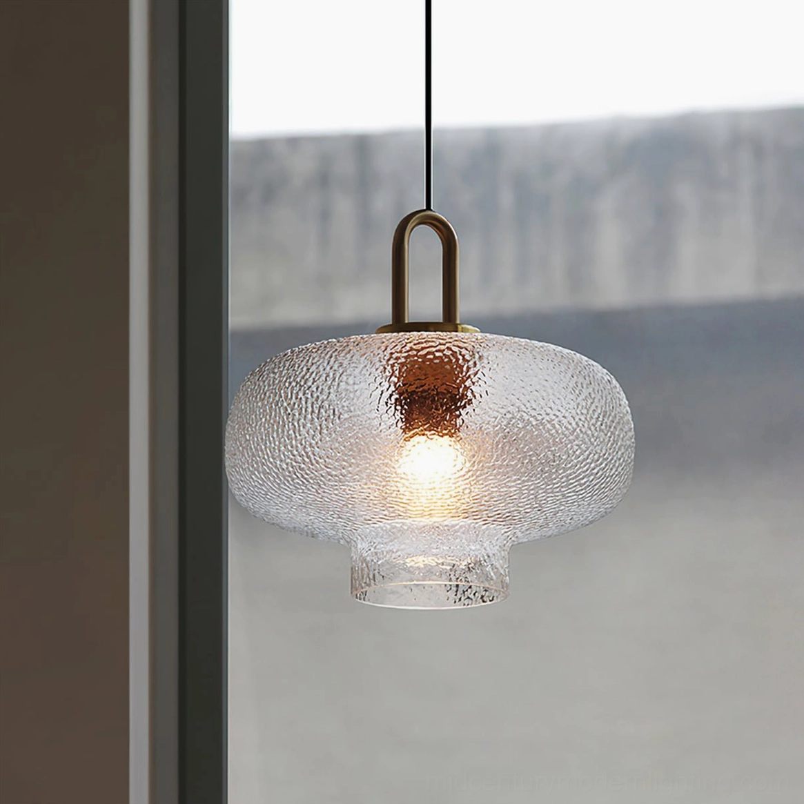 Wide flat-top Marco glass pendant with rippled clear glass and brass hardware, close-up view near window