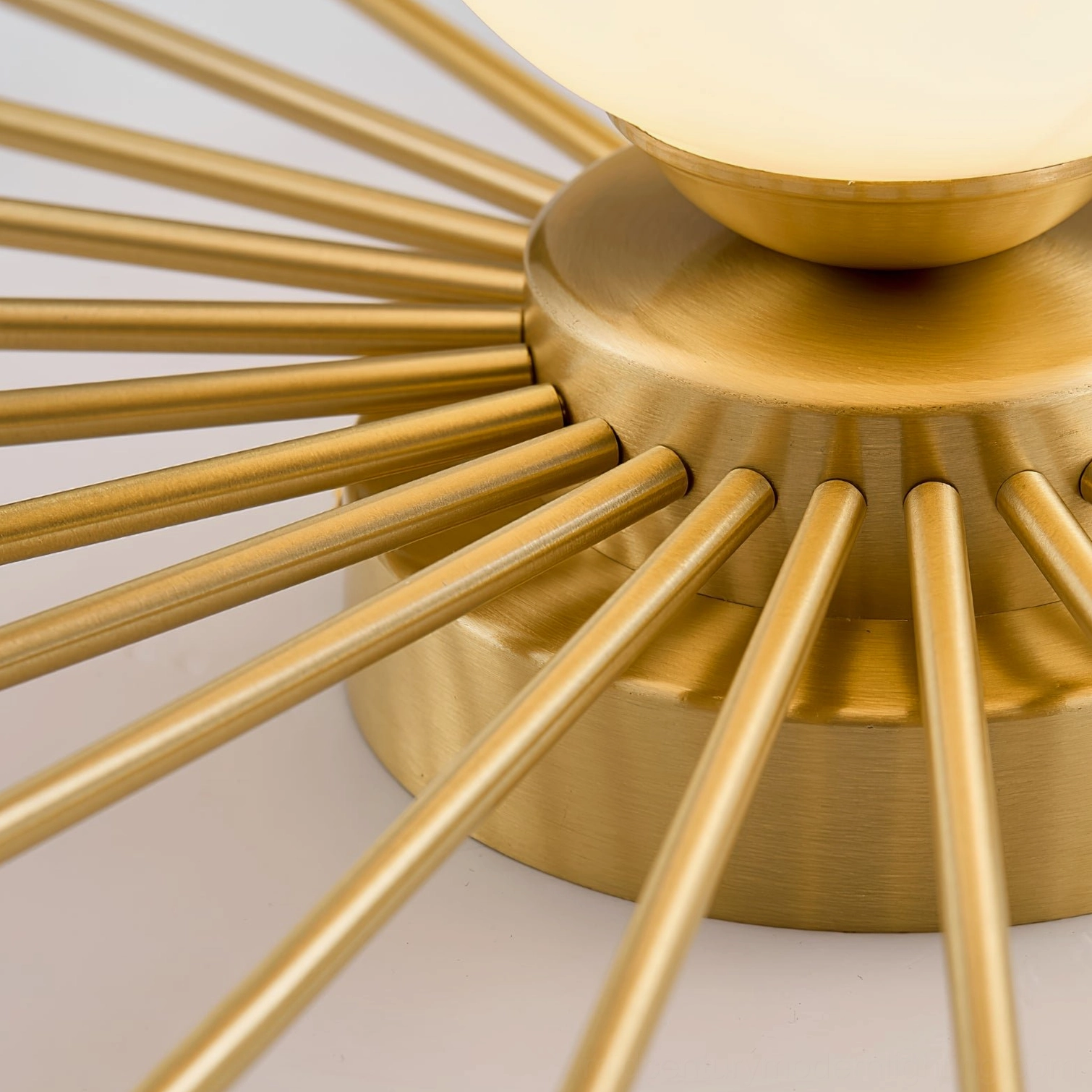 Close-up detail of Margaret ceiling light brushed brass base with radial spiked metal rods, sputnik design hardware