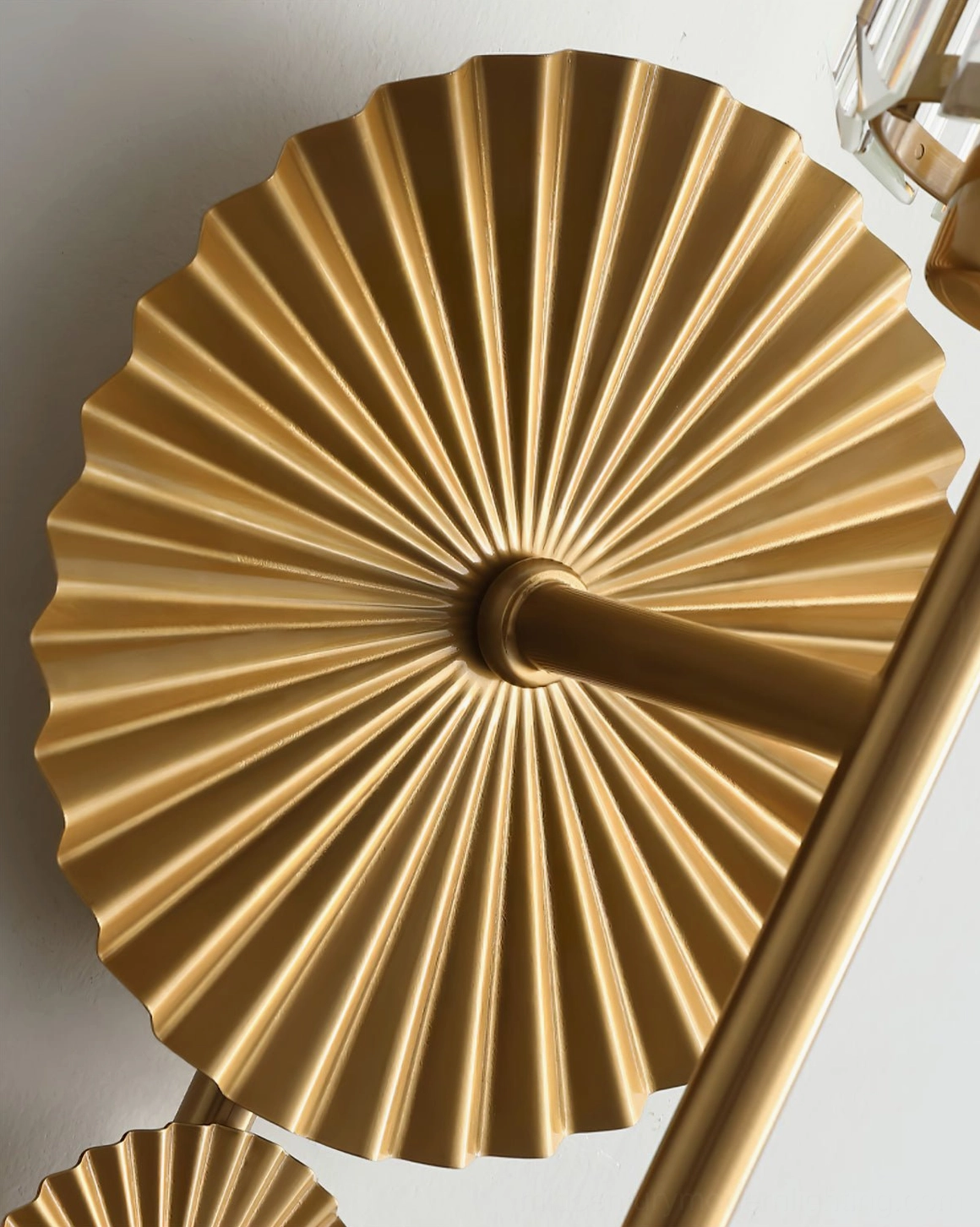 Close-up overhead view of Maria wall lamp radial pleated brass sunburst texture and metalwork detail
