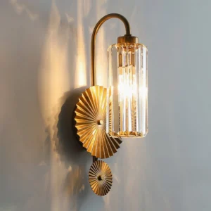 Maria wall sconce illuminated three-quarter angle showing warm glow through pleated glass, mounted on gray wall