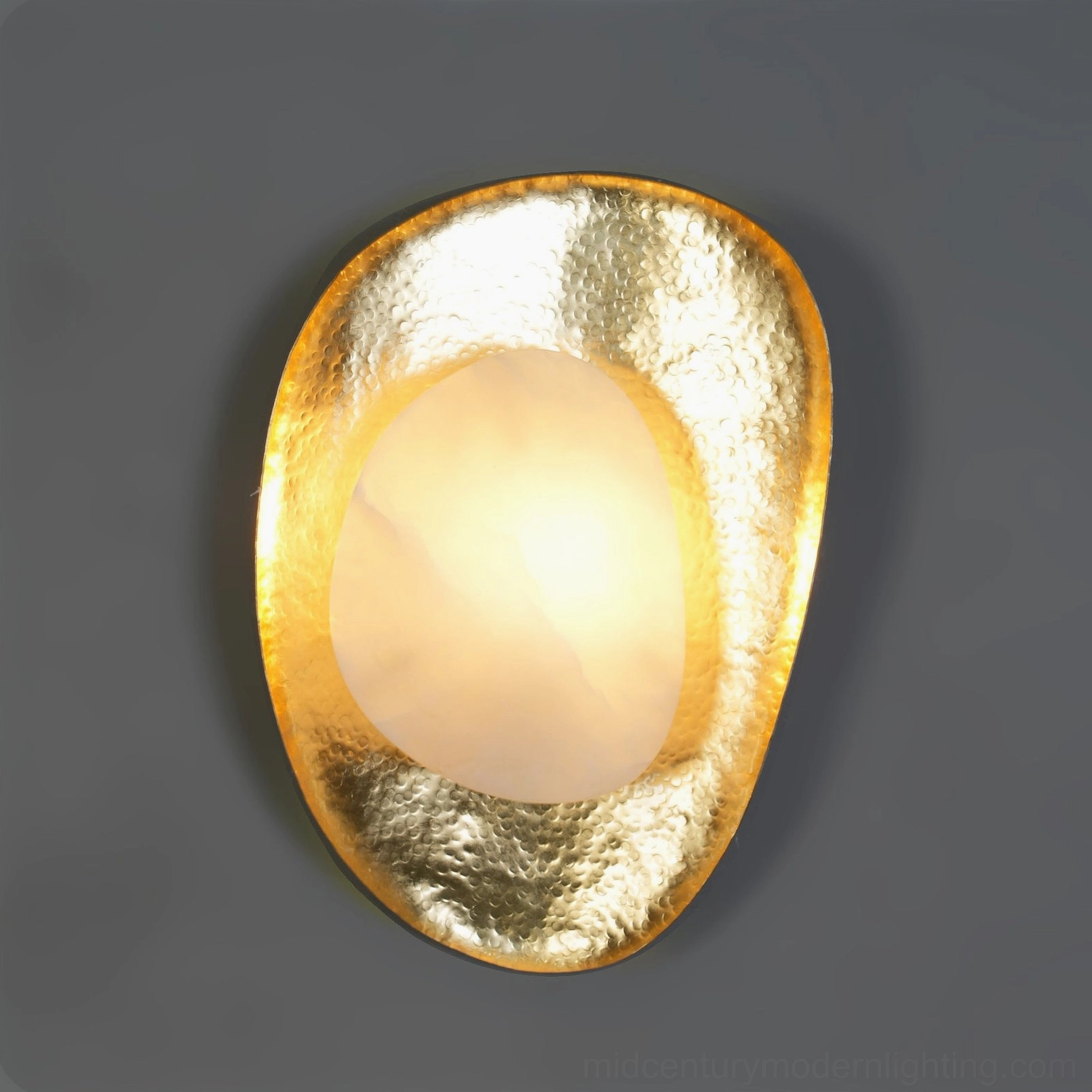 Oval wall sconce with glowing alabaster diffuser and hammered brass frame, studio lighting