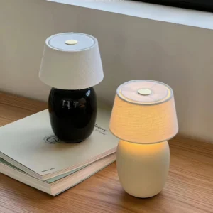 Two Marie table lamps with black and beige ceramic bases on wooden desk with illuminated lighting detail