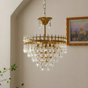 Marilyn Crystal Chandelier low-angle close-up detail, polished gold frame with dangling crystal droplets and refracted light on arched wall