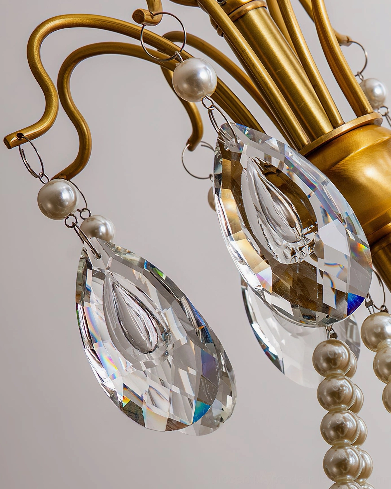 Detailed close-up of Mariposa chandelier brass arm with crystal pendants and pearl bead decoration