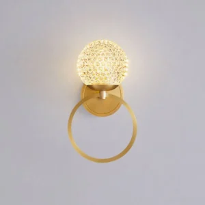 Marni Wall Sconce spherical crystal glass shade with warm ambient glow on light gray wall - contemporary brass wall lamp
