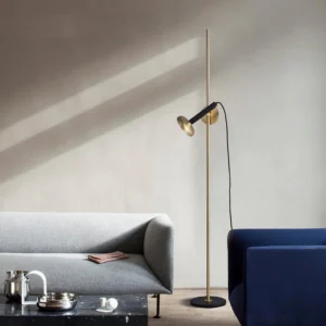 Marquina floor lamp in modern Nordic minimalist living room with neutral sofa, eye-level view showing warm brass and black design